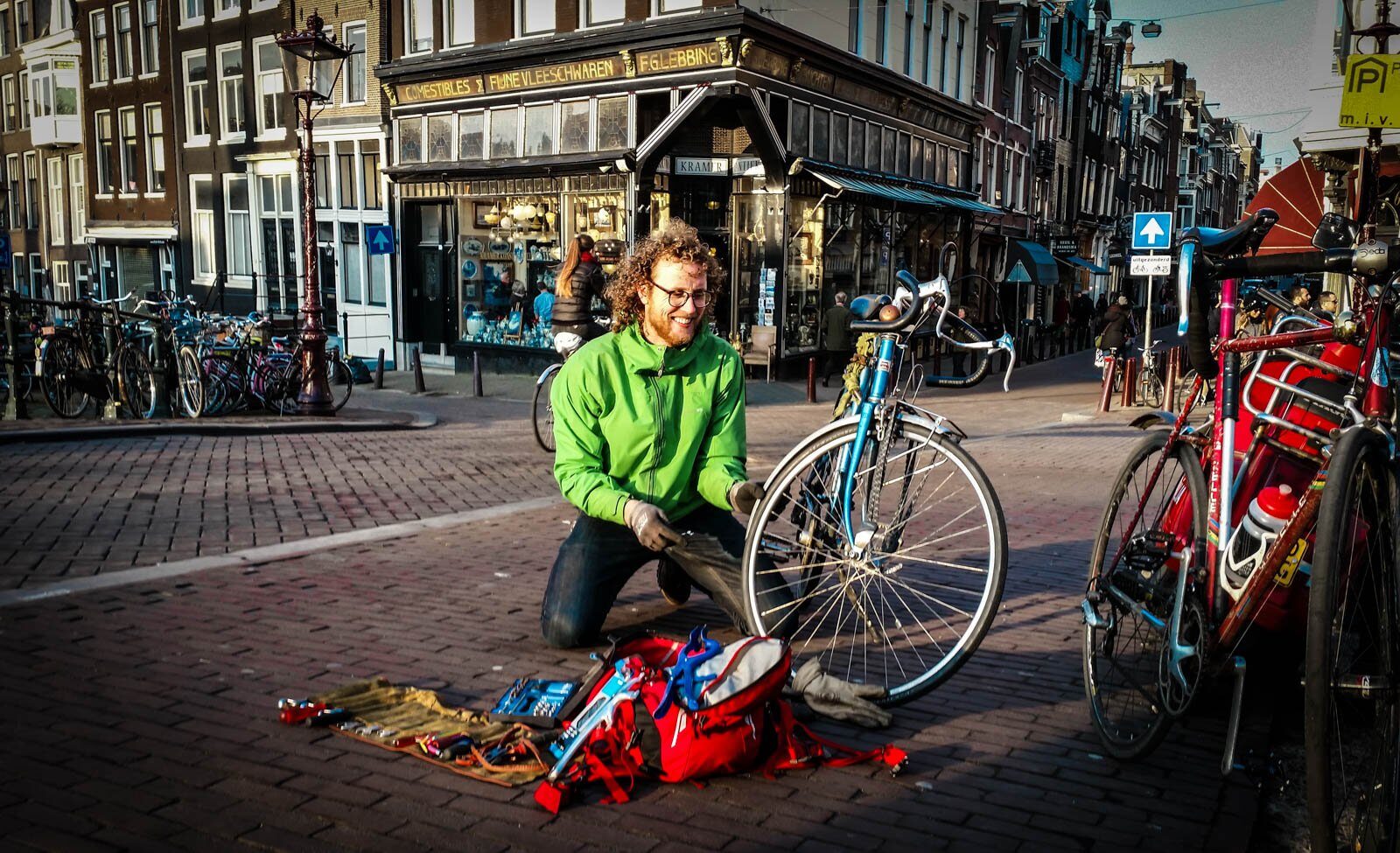 Alex repareert een fiets op straat in de Amsterdamse binnenstad
